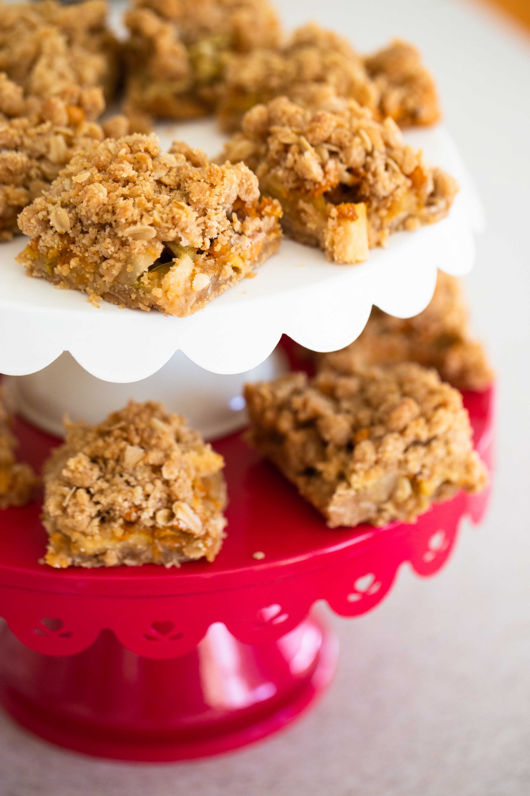 The tiered dessert stand has several squares of apple crisp bars ready for the party.