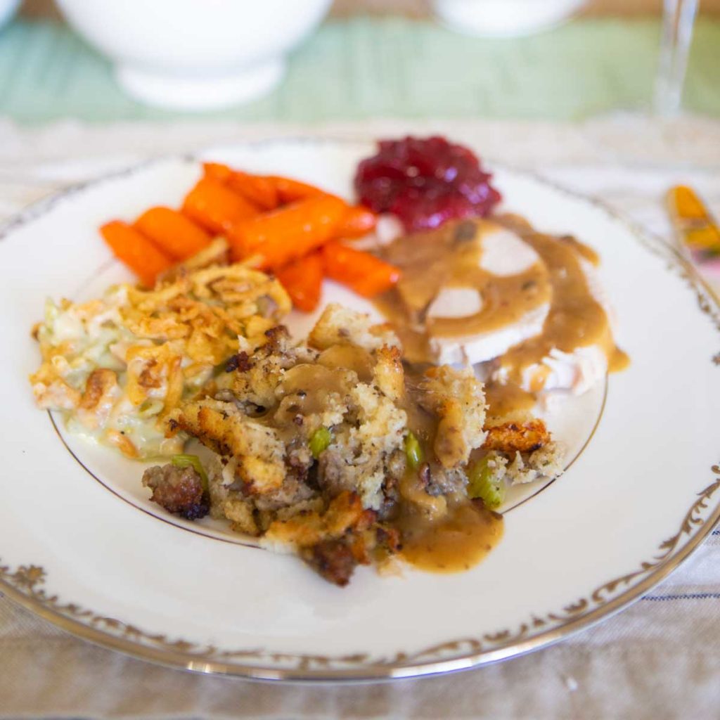 A full plate of Thanksgiving dishes drizzled with homemade gravy.