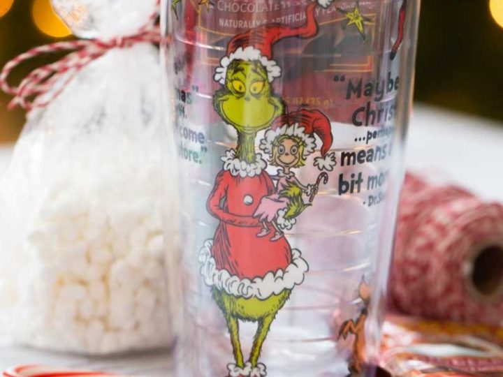 A Grinch tumbler with a bag of marshmallows and mini candy canes.