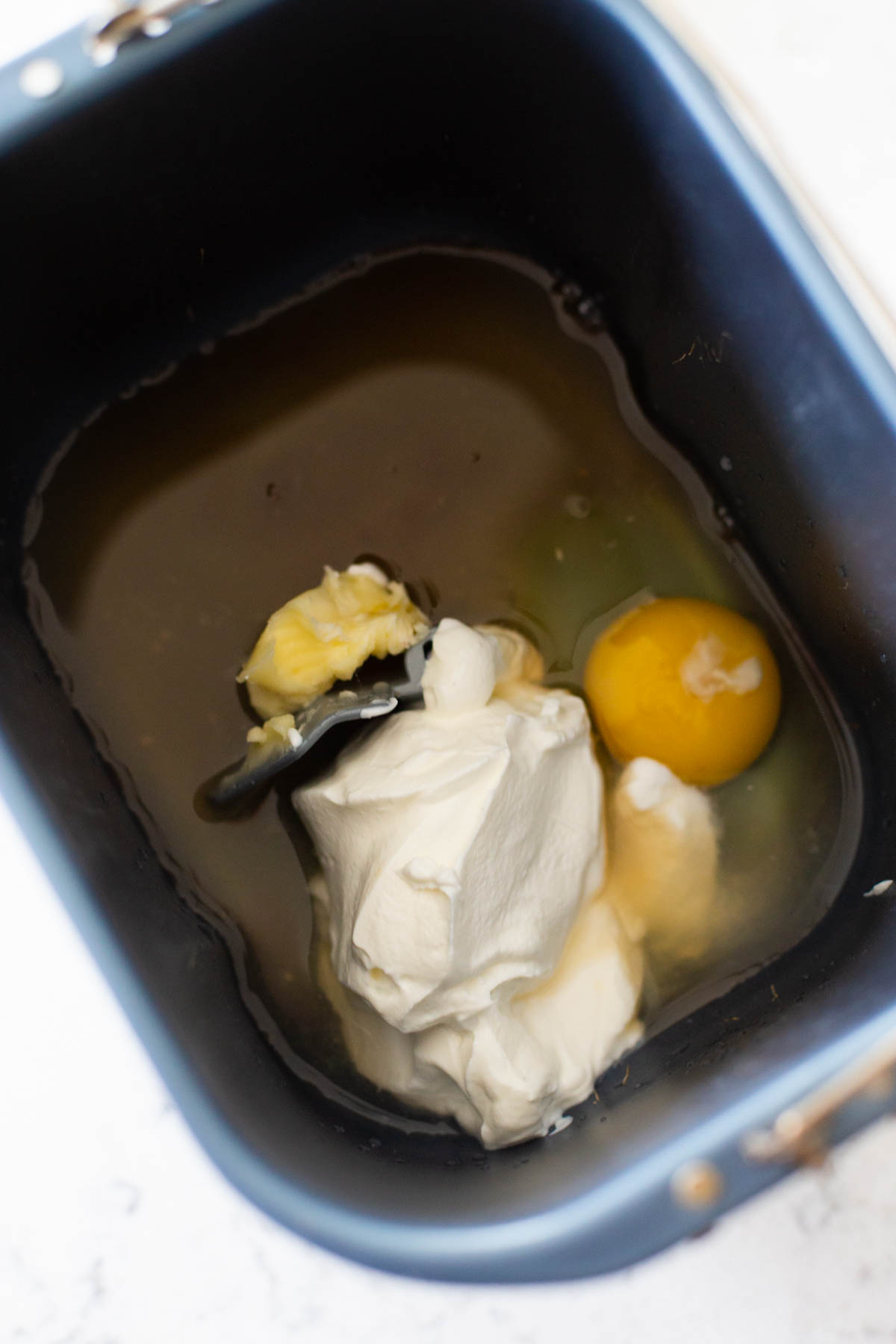The bread pan is filled with the wet ingredients including eggs and sour cream.