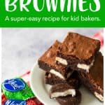 The brownies have been sliced and stacked on a white plate next to the chocolate candies tucked inside.