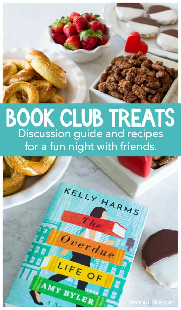 Book Club Treats on display include pretzels, strawberries, candied nuts, and black and white cookies next to the book of the month: The Overdue Life of Amy Byler