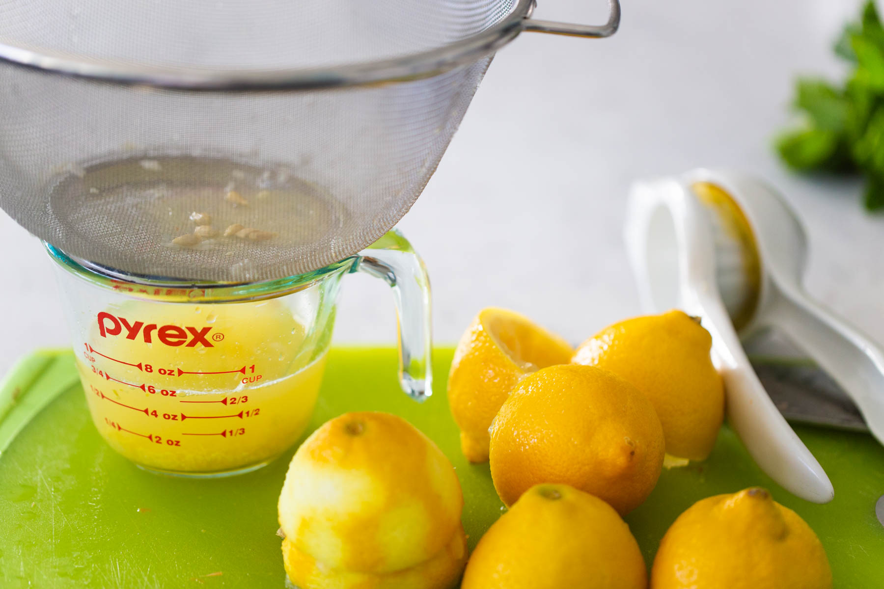 The lemons have been cut and squeezed over a measuring cup.