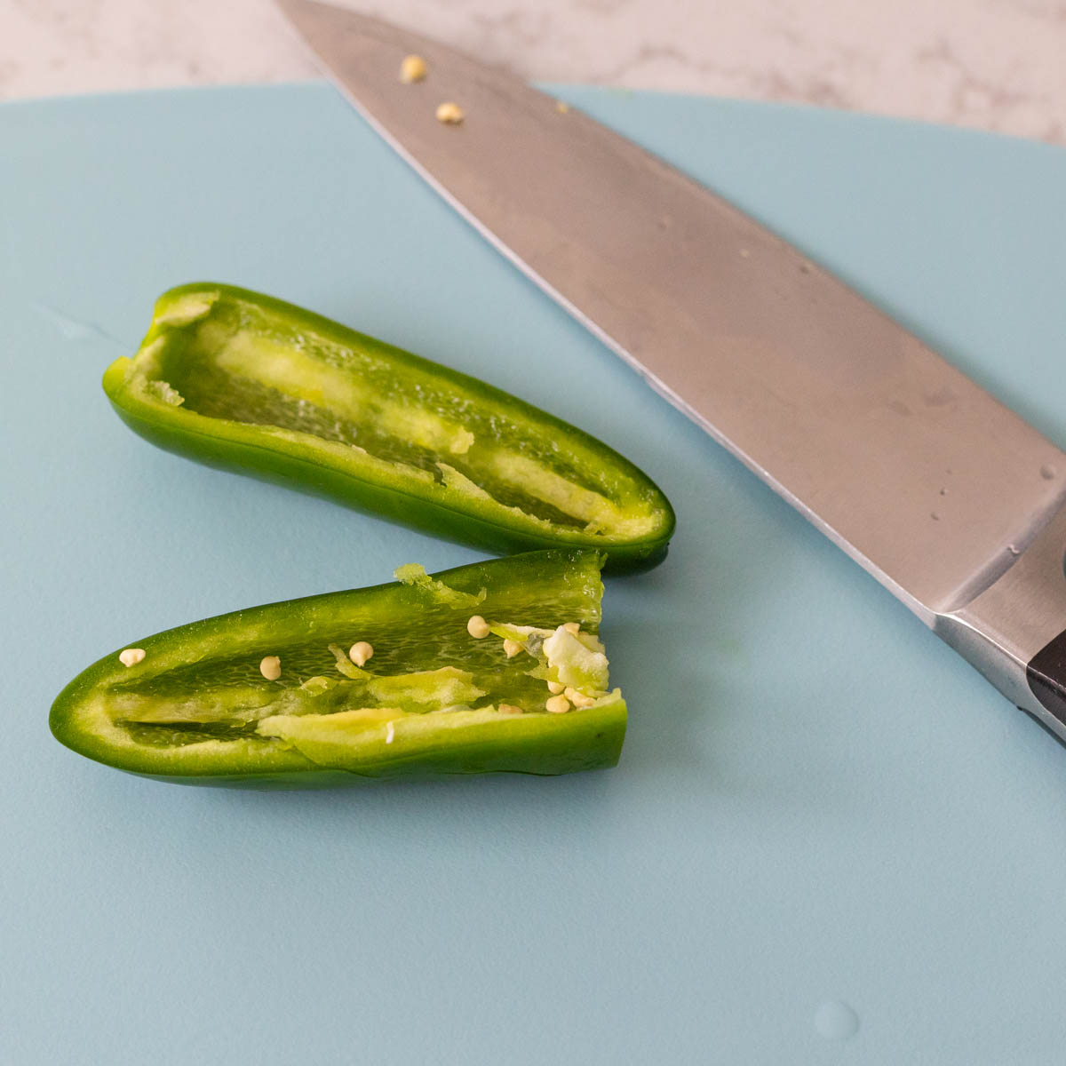 the Jalapeño has been sliced in half on a cutting board.