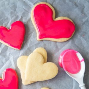 How to host a cookie decorating party for Valentine's Day. Sugar cookies with pink icing and a spoon.