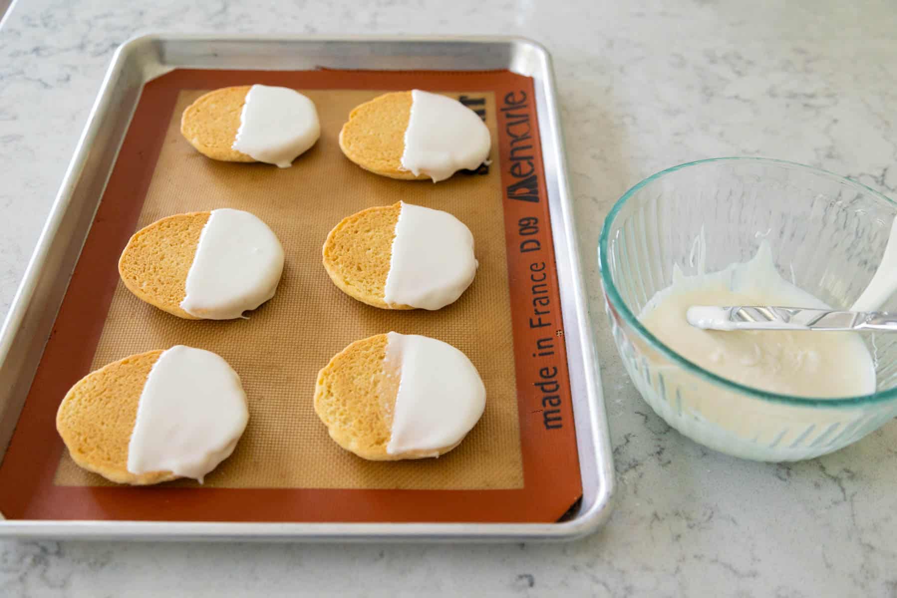 The pan of cookies has been frosted just on one half with white icing.