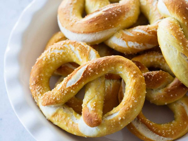 A pie plate holds a pile of baked fluffy pretzels with chunks of kosher salt sprinkled over the top.
