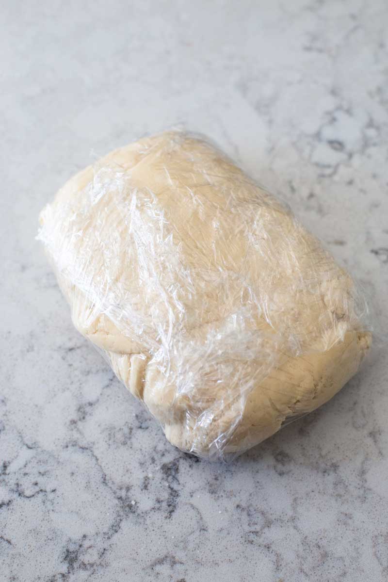 Pie crust dough has been wrapped in plastic wrap.