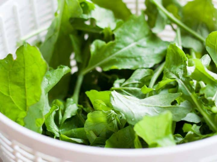 A salad spinner basket holds freshly washed lettuce leaves.