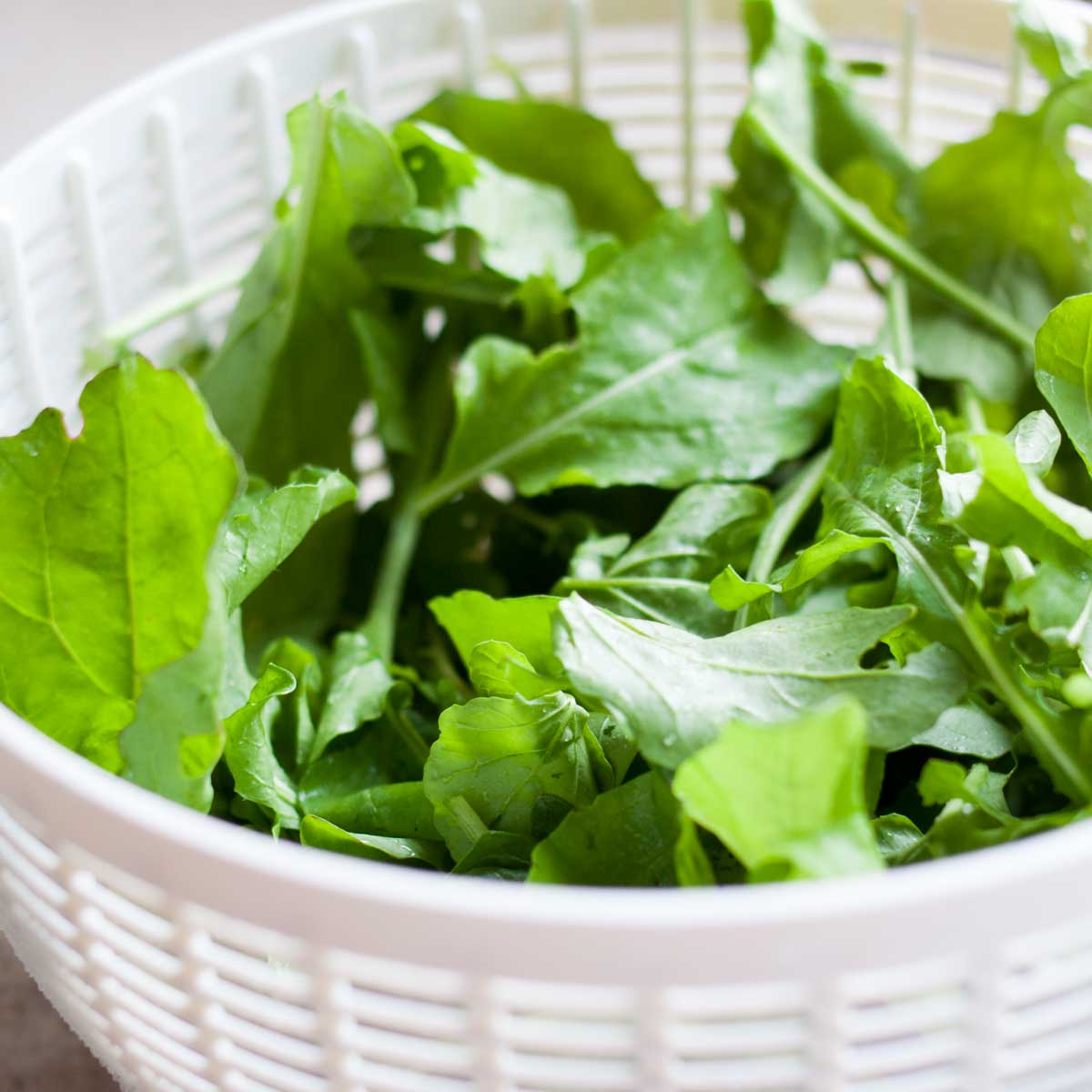 A salad spinner basket holds freshly washed lettuce leaves.