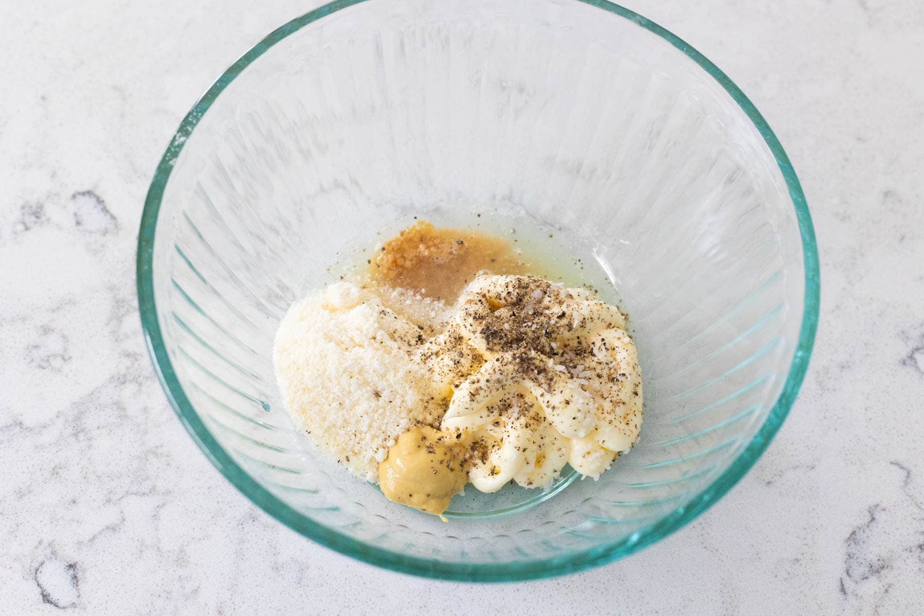 The mayo, parmesan, and other ingredients have been measured into a small mixing bowl.