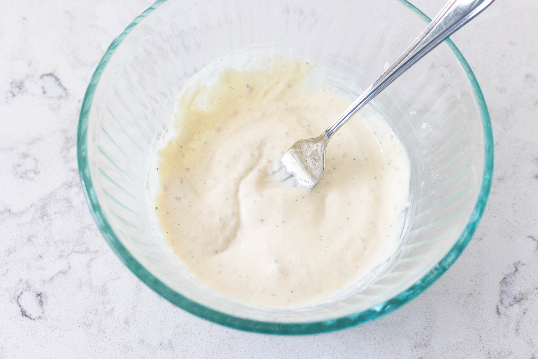The dressing has been whisked together with a fork and is creamy and smooth.