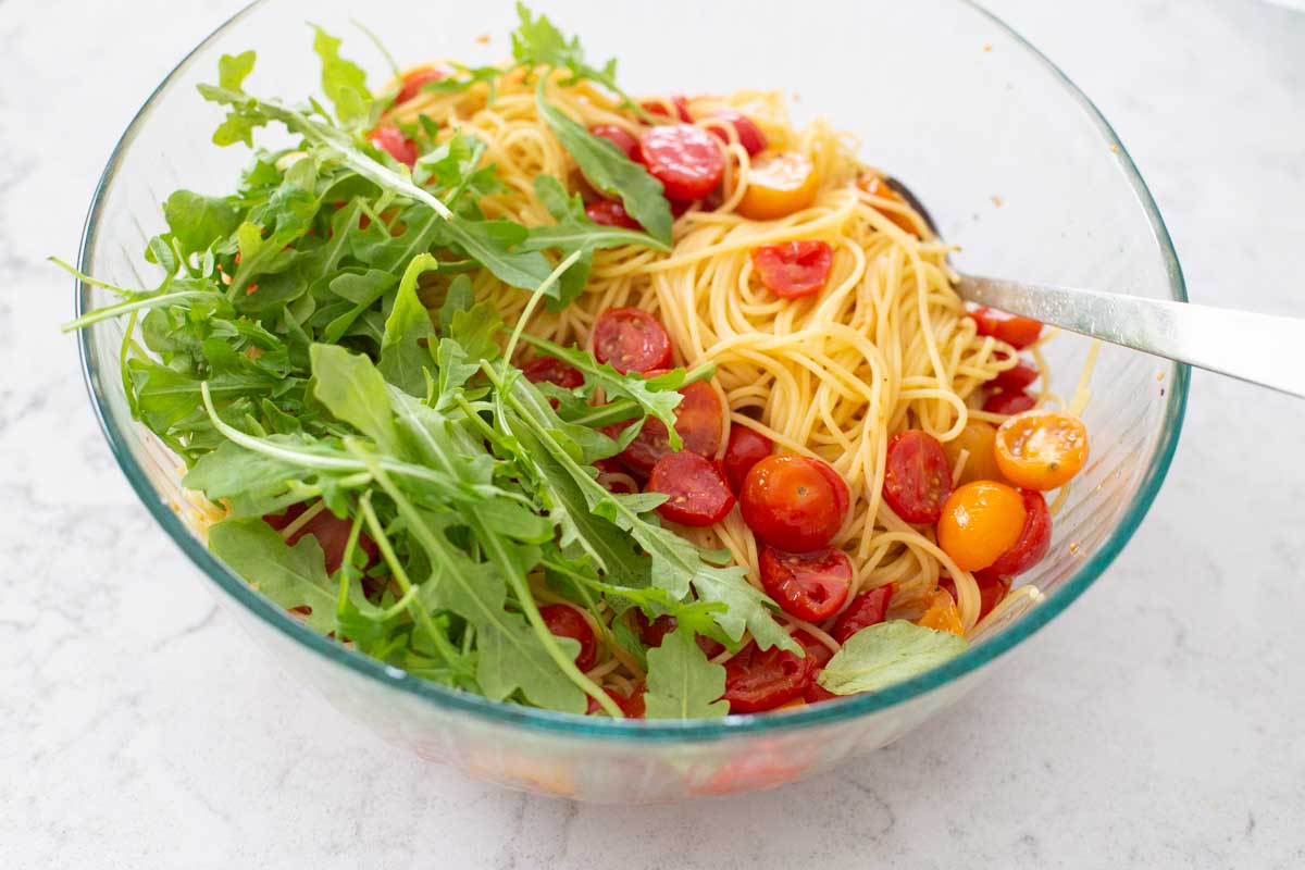 The pasta and fresh arugula were added on top of the tomatoes.