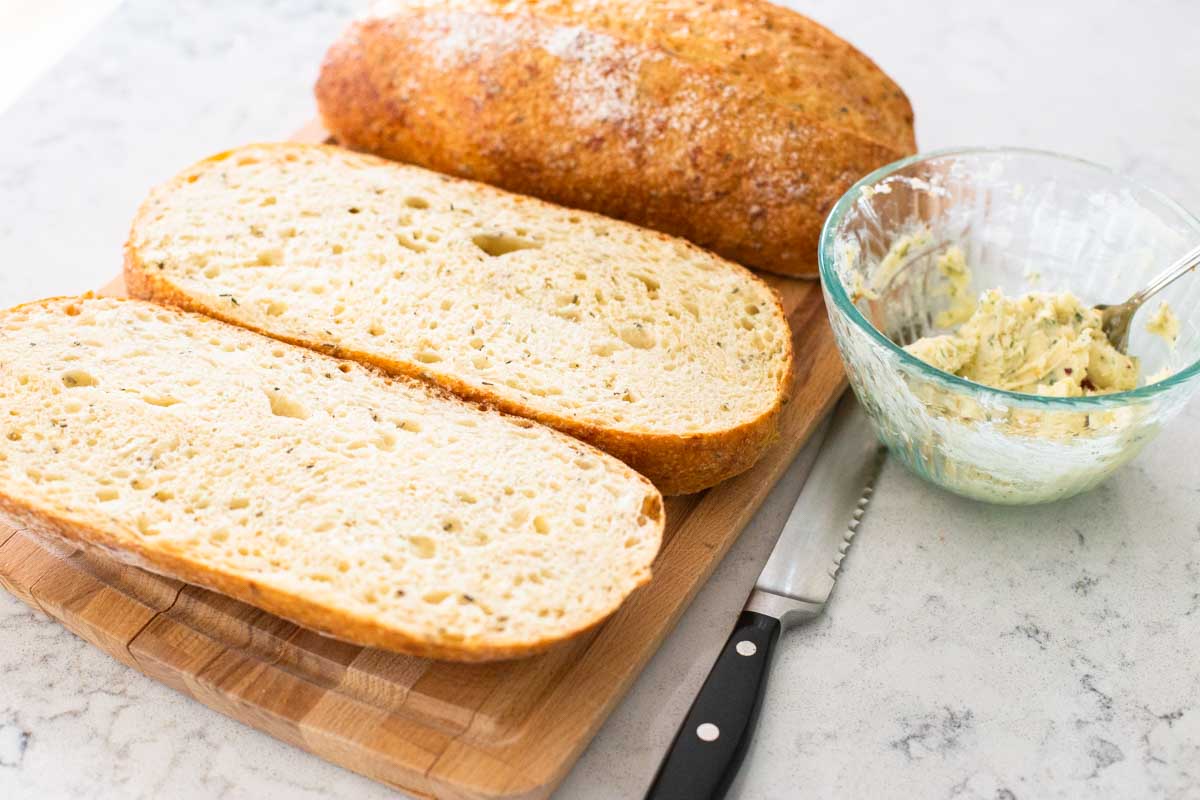 A large Italian loaf has been sliced in half for turning into garlic bread.
