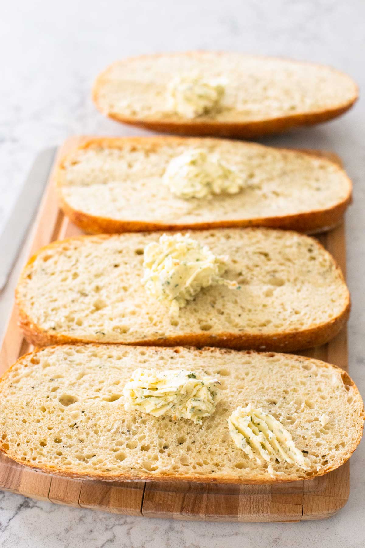Dollops of garlic butter have been divided among halves of bread.