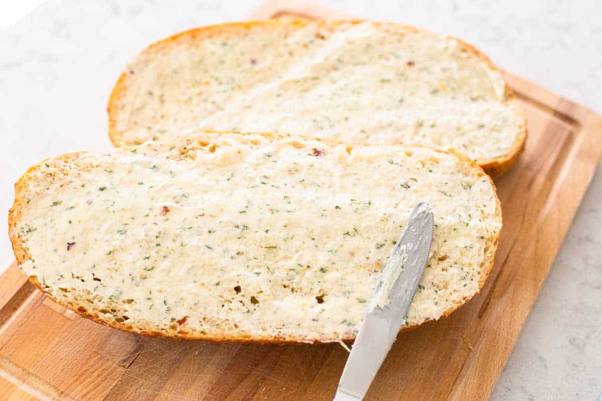 The loaves of bread have the butter spread from edge to edge.