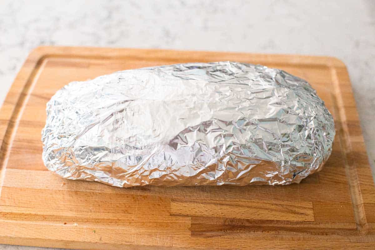 The prepared garlic bread has been wrapped tightly in foil for the freezer.