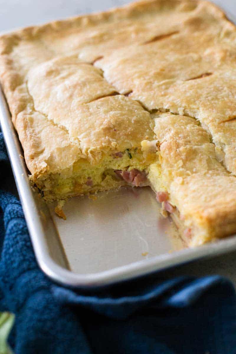 The baked ham and egg pie has a slice cut out and served.
