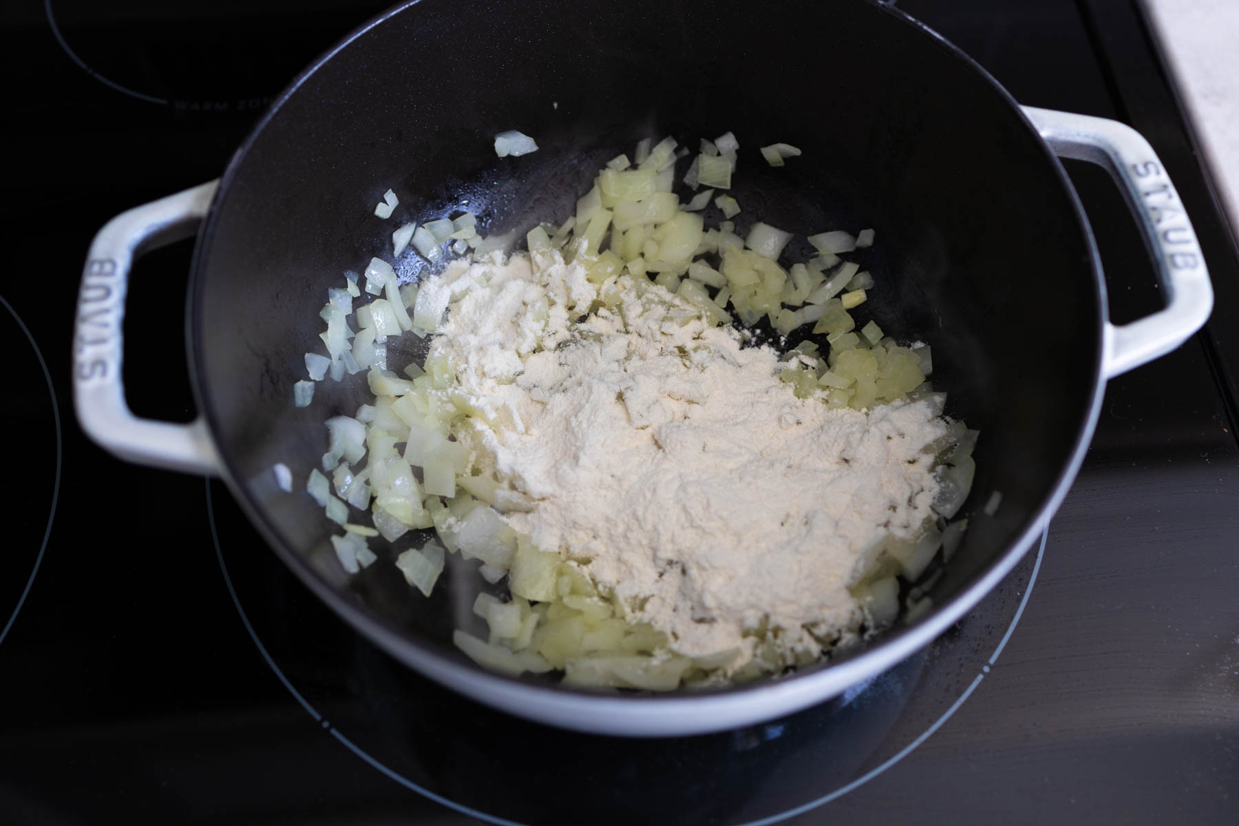 The chopped onion has been cooked, flour is now sprinkled over the top.