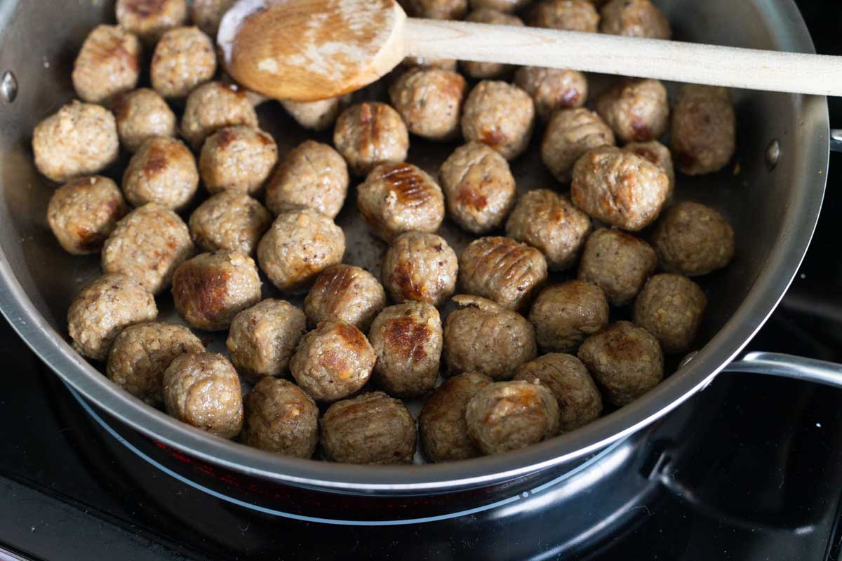 The frozen meatballs have been browned in a large skillet.