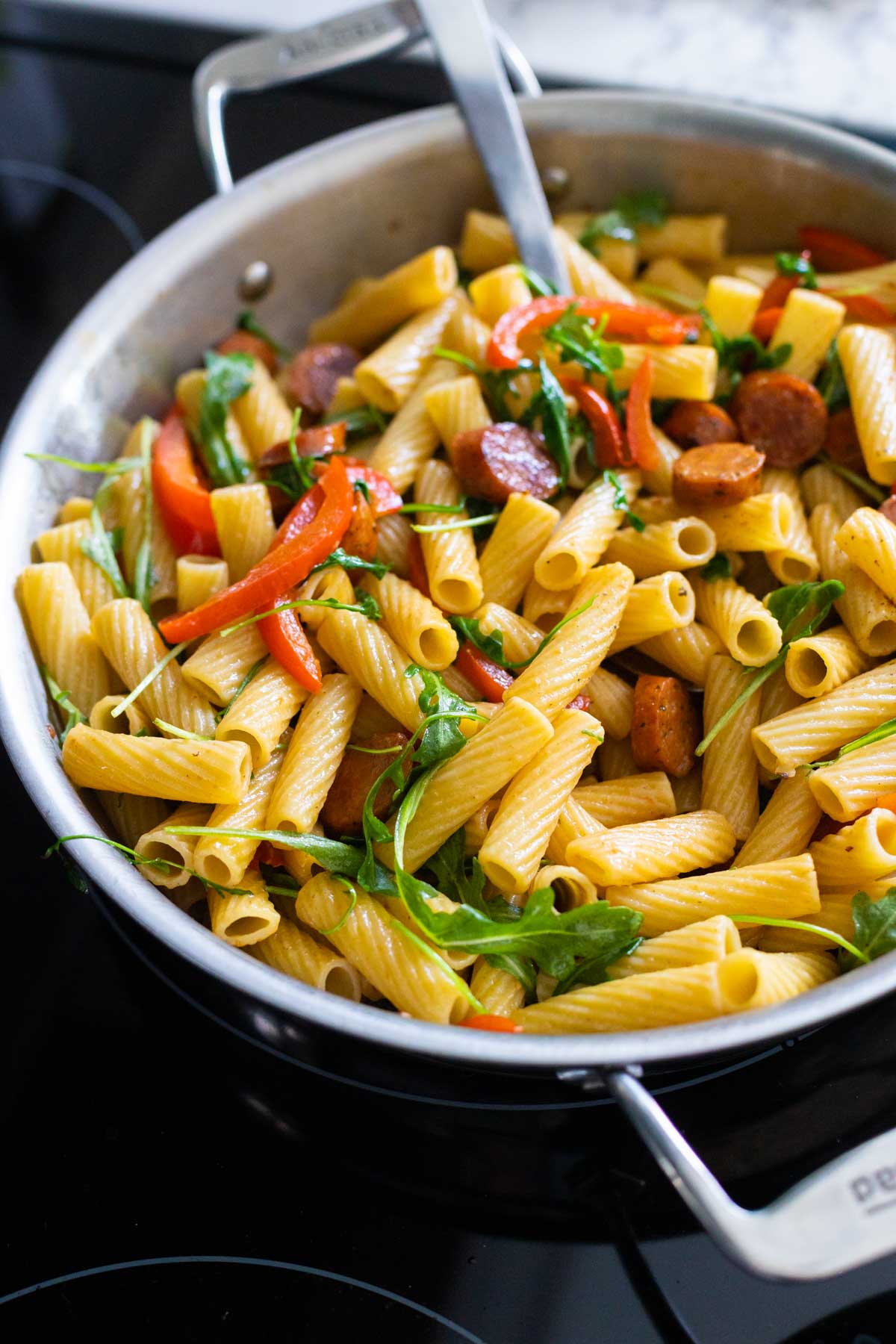 The skillet has the finished sausage and peppers pasta ready to serve.