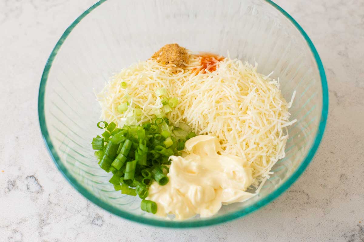 The shredded cheese, mayo and seasonings are in a mixing bowl.