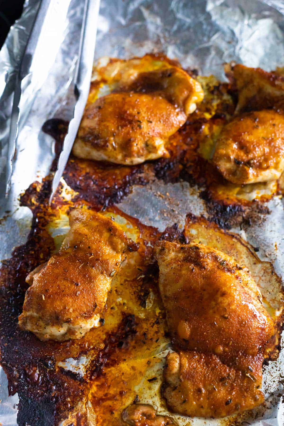 The baked blackened chicken thighs are cooling on the roasting pan.