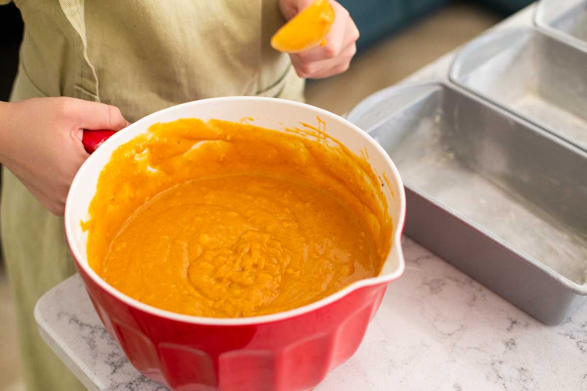 A baking bowl is filled with pumpkin bread batter about to be poured into the pans.