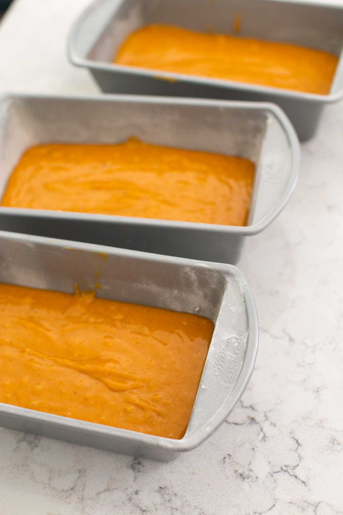 The 3 pans are filled evenly with pumpkin bread batter.