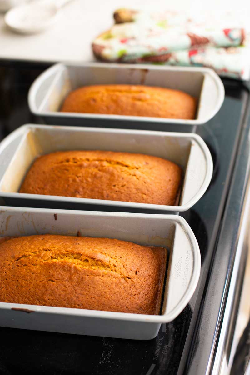 The pumpkin bread loaves have been baked and are cooling on the stovetop.