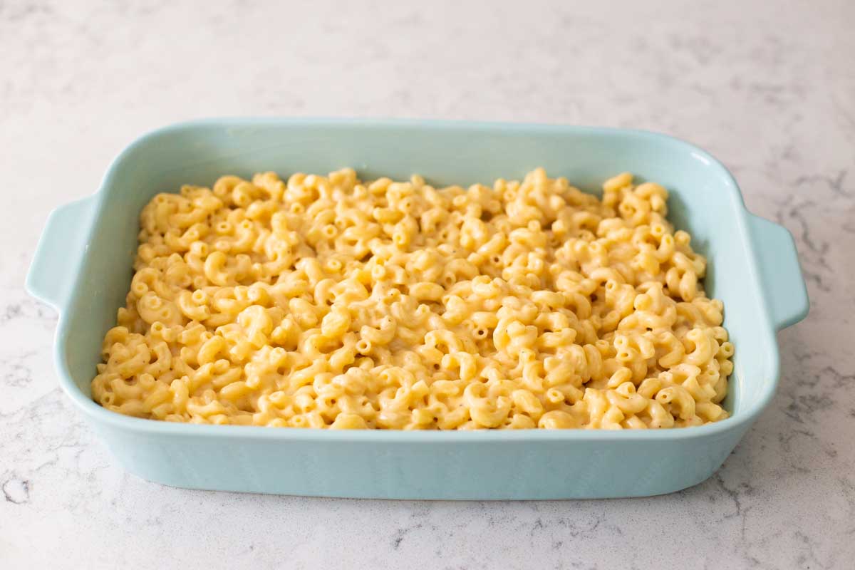 A blue baking dish has a casserole of mac and cheese.