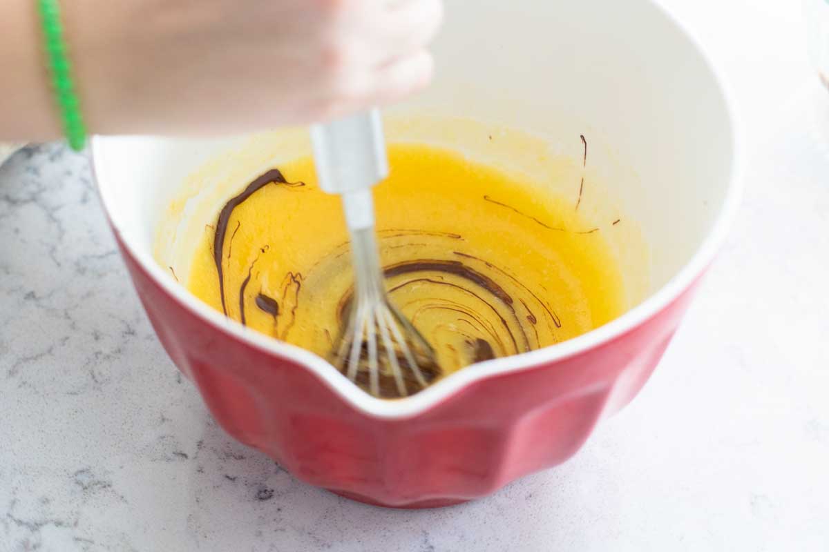 The melted chocolate is being whisked into the egg and sugar mixture.