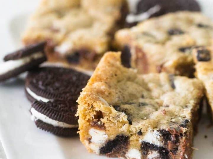 A tray of cookies and cream bars have OREOS sitting next to them.