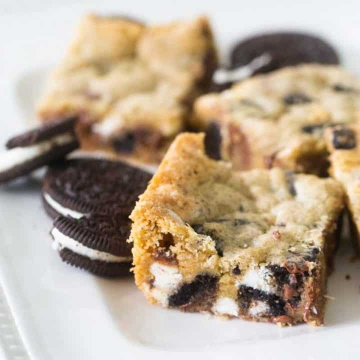 A tray of cookies and cream bars have OREOS sitting next to them.