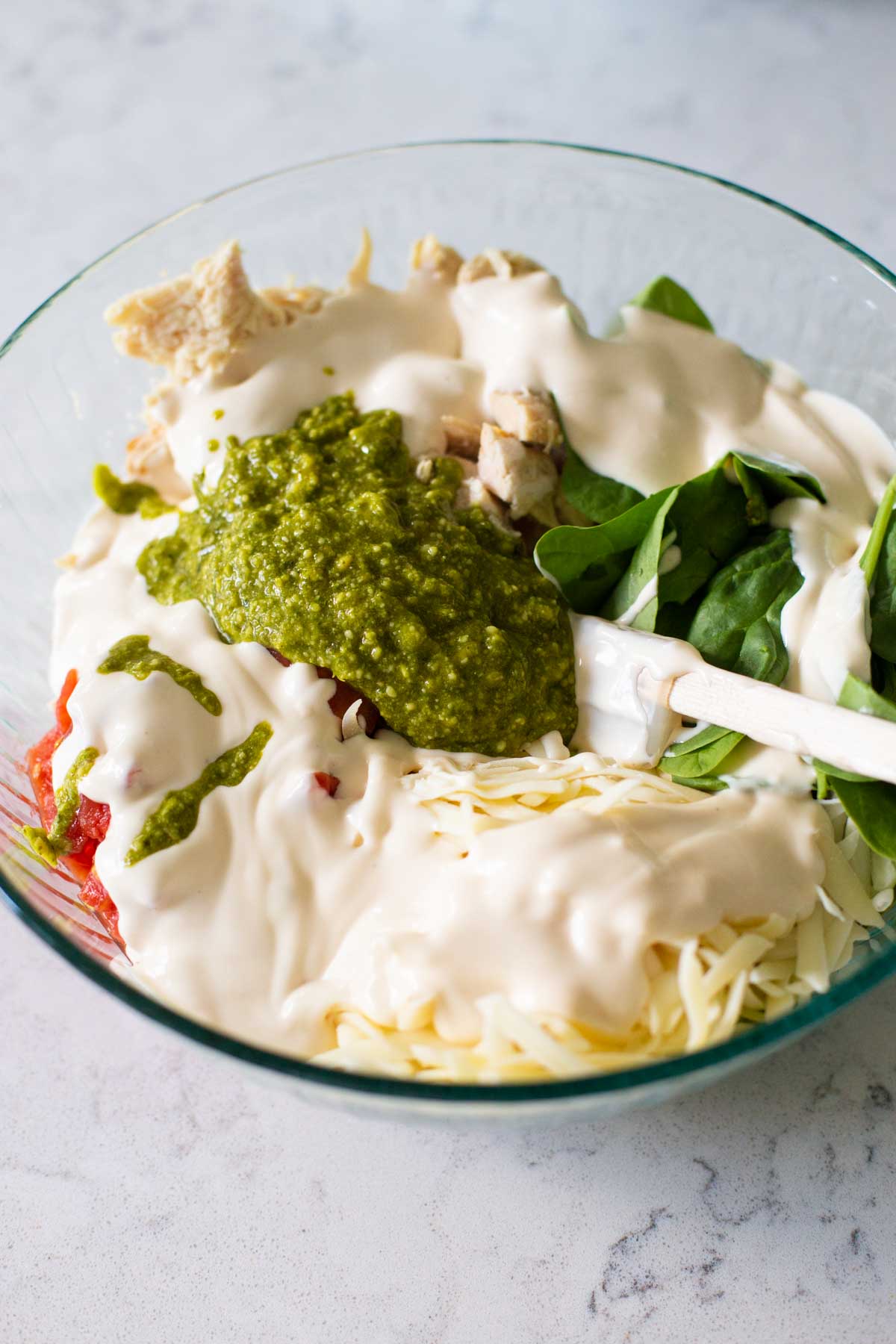 The alfredo sauce and pesto sauce have been added to the mixing bowl.
