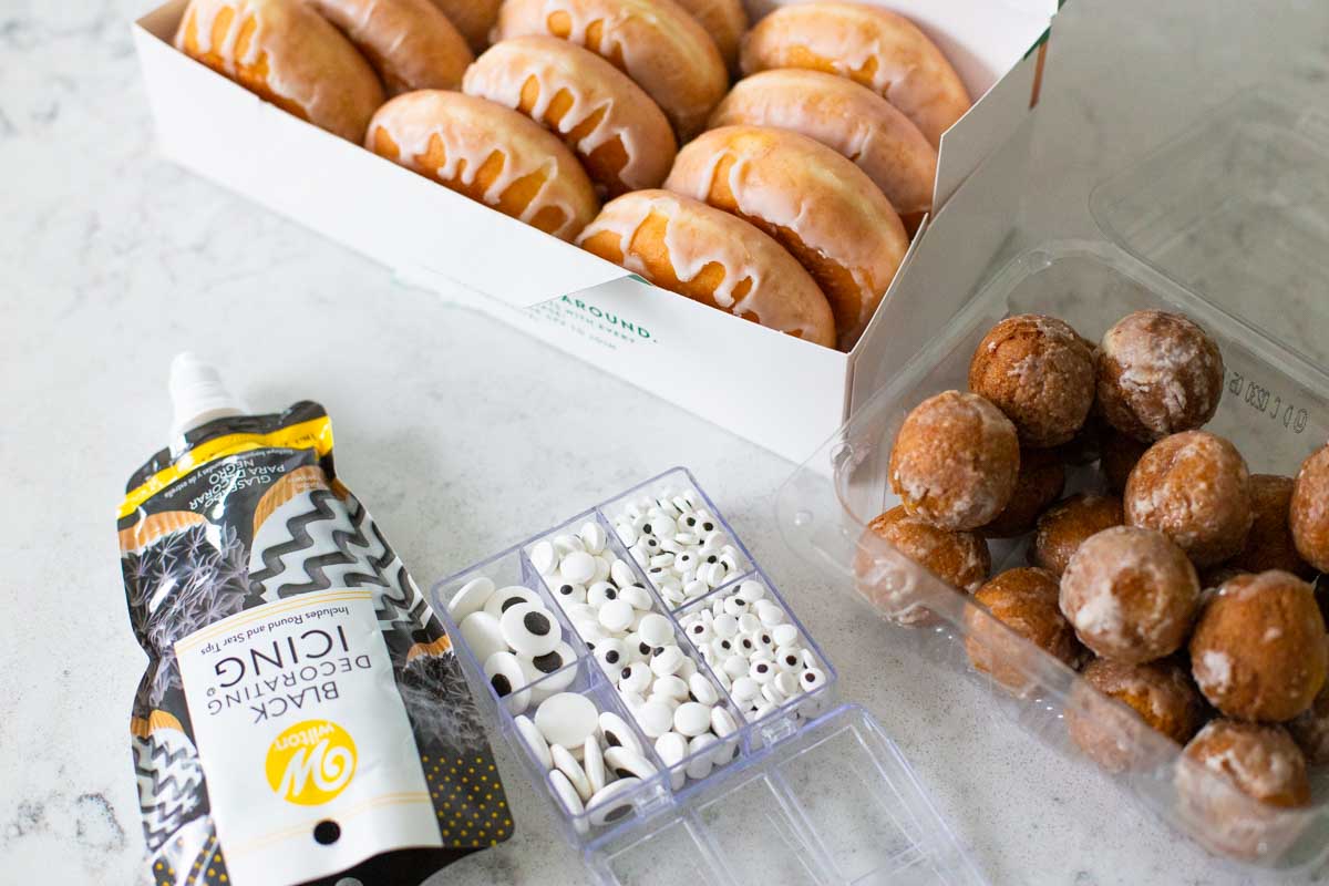 The tools to make Halloween donuts are on the counter next to a box of donuts.