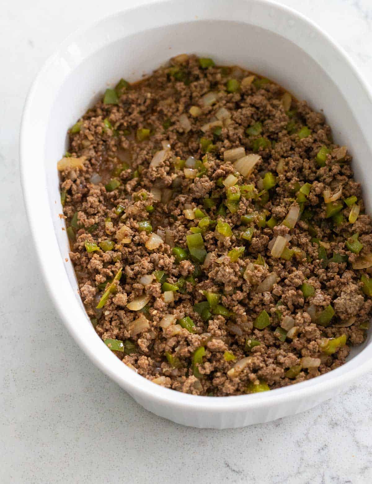 The white storage dish is filled with the beef sandwich mixture.