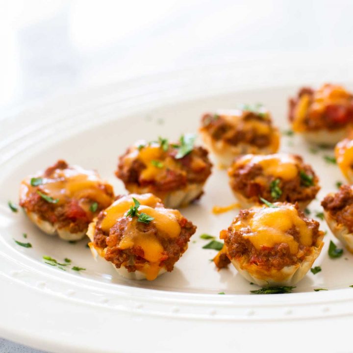 Bite-sized taco phyllo dough cups with melted cheese on top.
