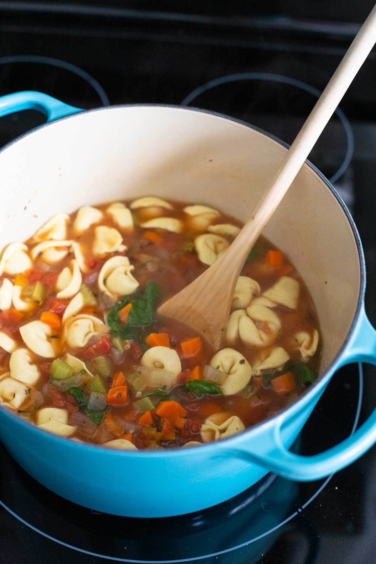 The tortellini soup is simmering in a large blue pot.
