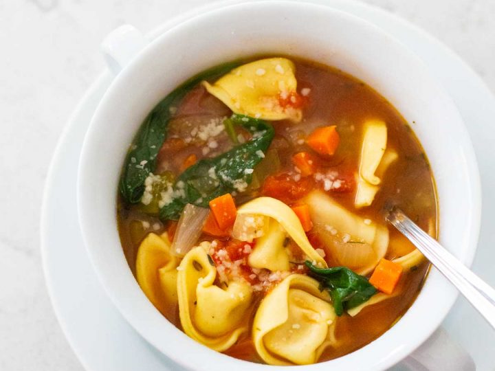 A light and healthy tortellini soup has spinach and carrots floating in the broth.