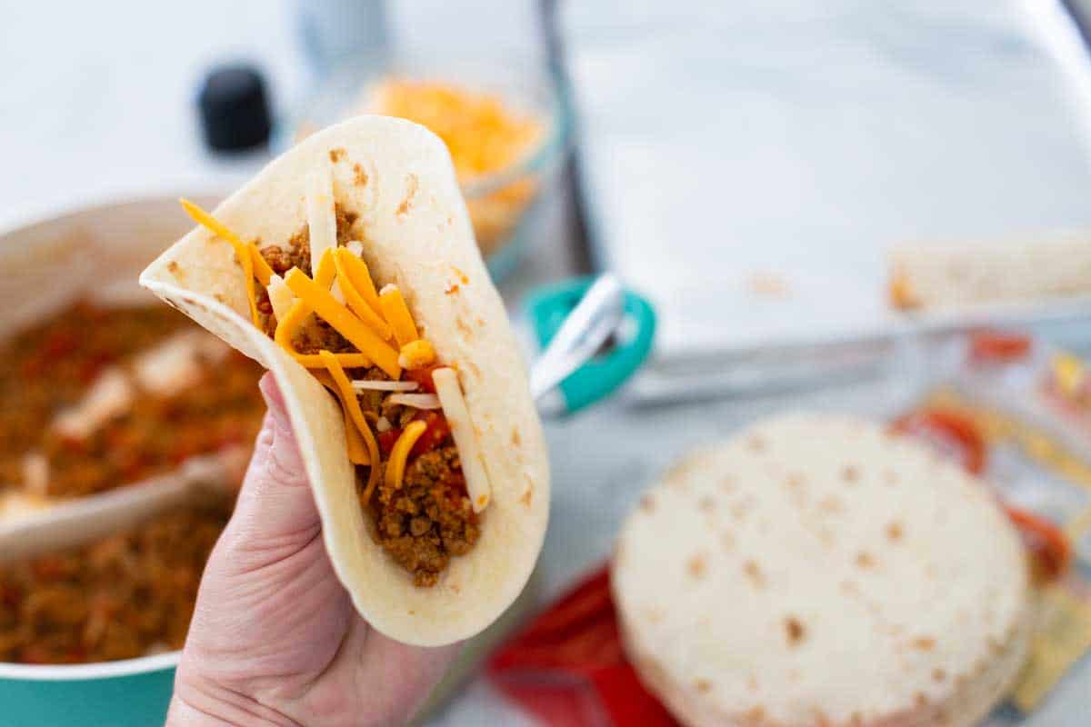 A hand shows how much filling to add to the turkey taquito