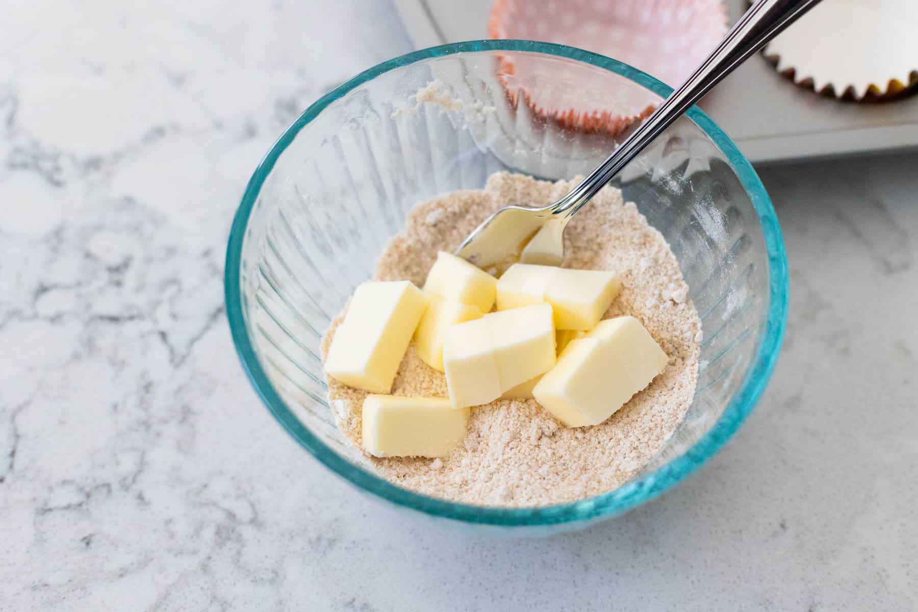 A mixing bowl filled with chopped butter and a sugar mixture.