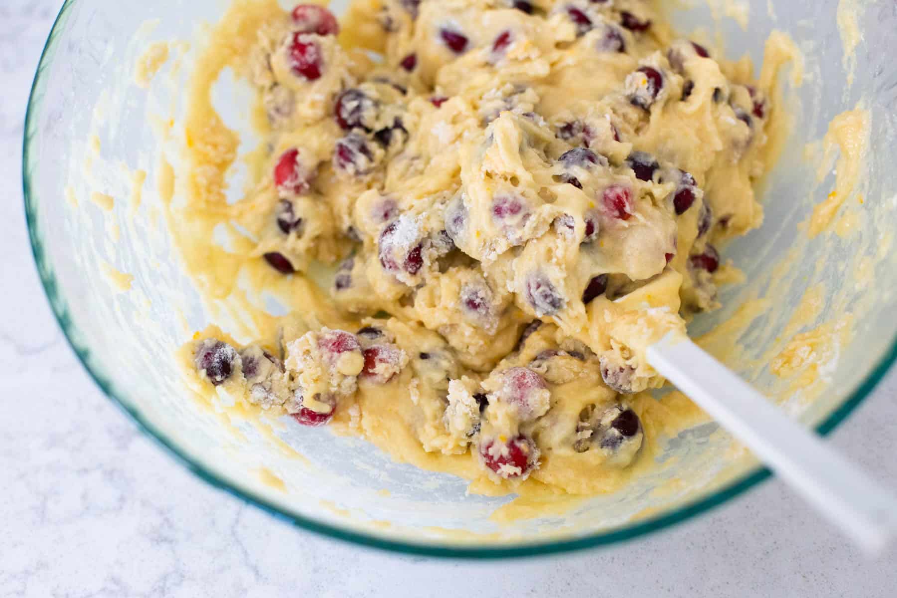 The liquid batter has been mixed with the dry ingredients and the mixture is now much thicker.  You can see the fresh cranberries peeking through.