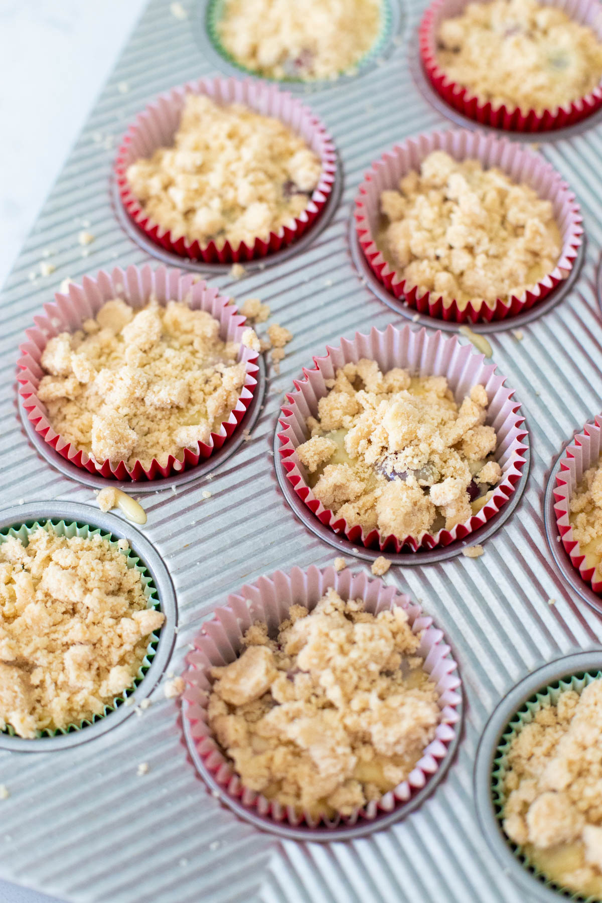 The streusel topping has been sprinkled over each muffin well.