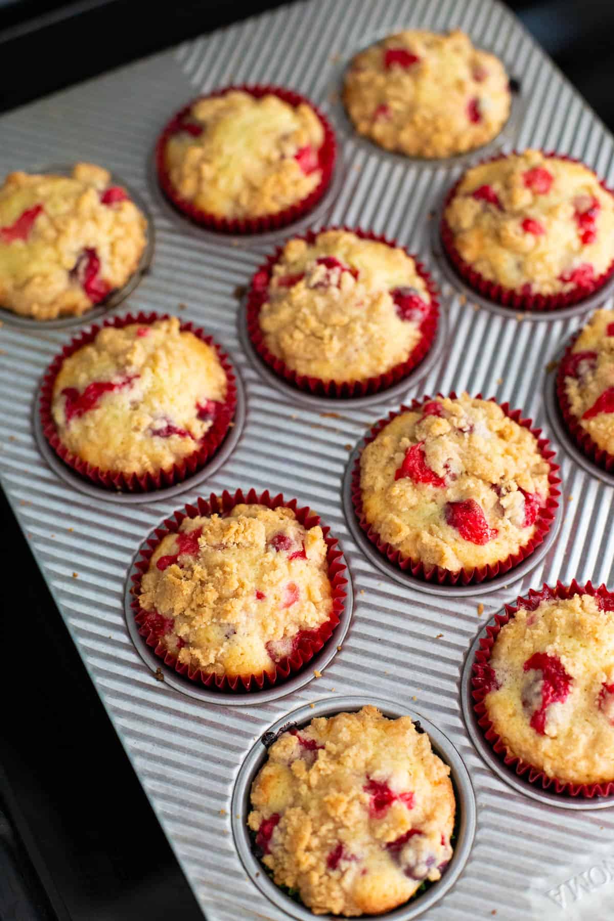 The muffin tin has just come out of the oven and the muffins are golden brown.