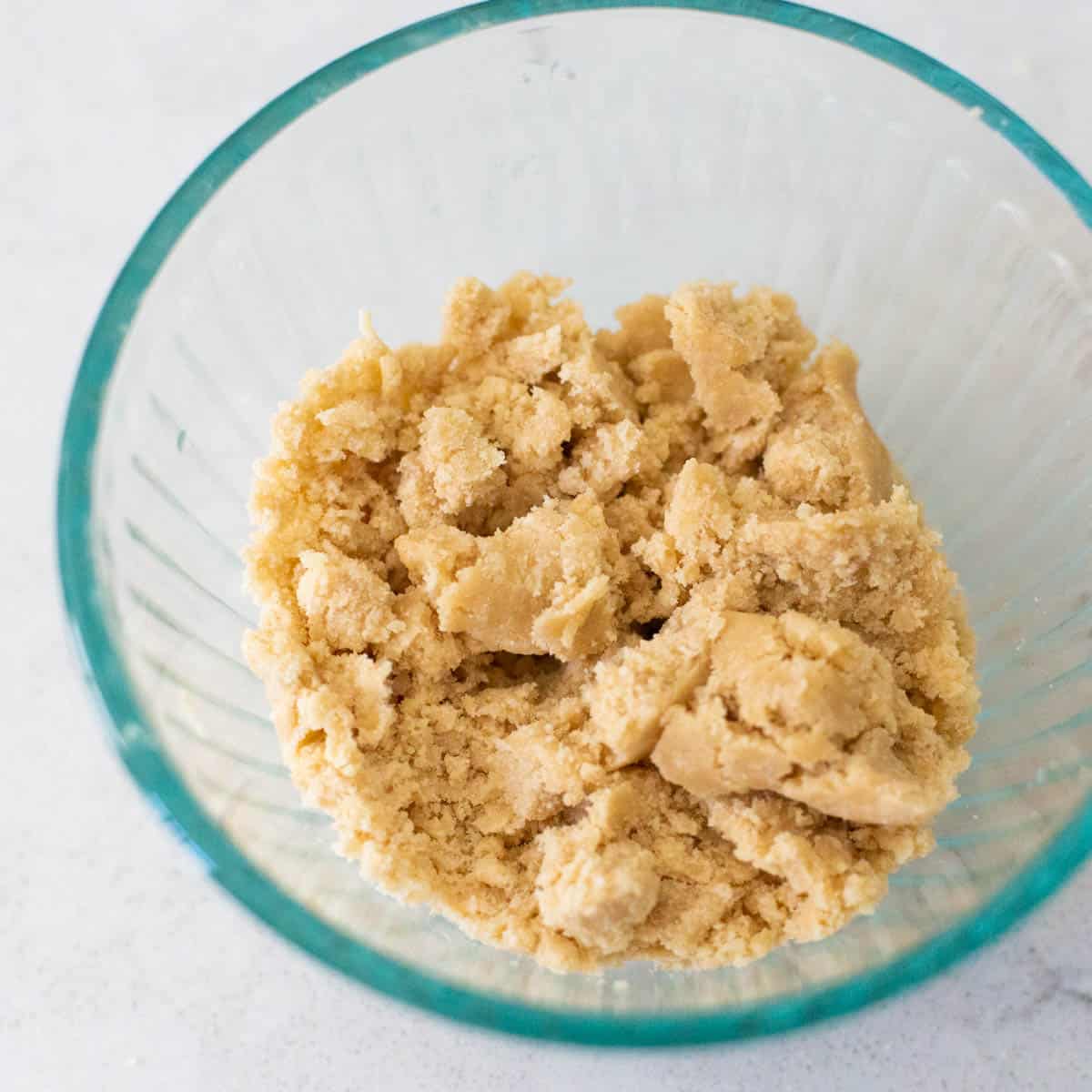 The mixing bowl is filled with the prepared streusel topping before being pinched together over the muffins.