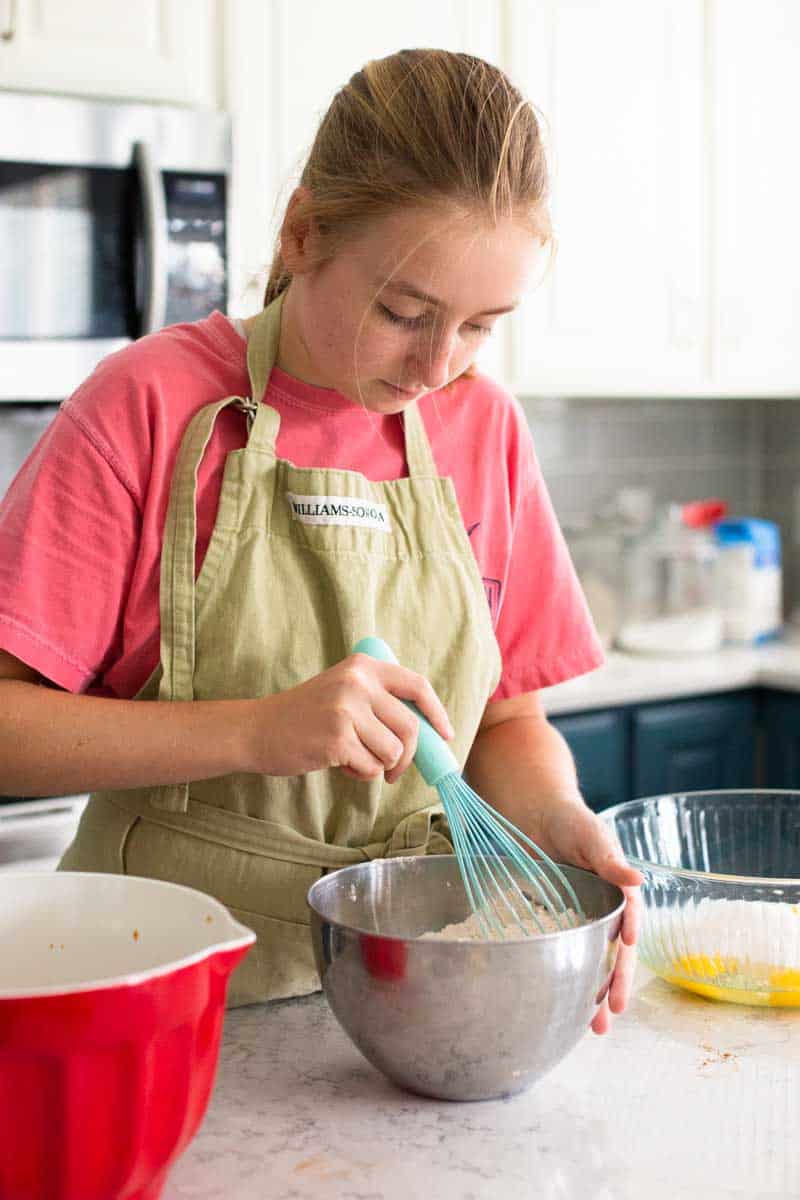 A girl is mixing up the cookie dough batter in the kitchen.