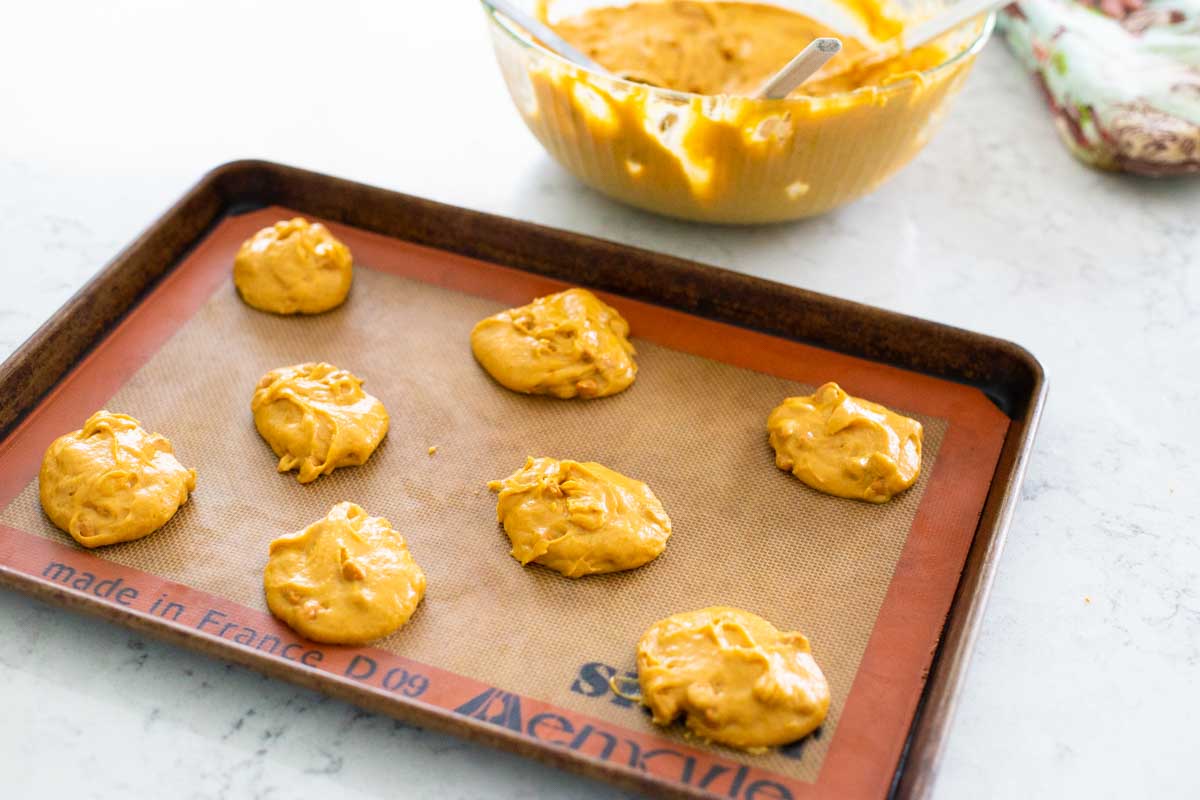 The baking pan has a batch of pumpkin butterscotch cookies dropped onto it for baking.
