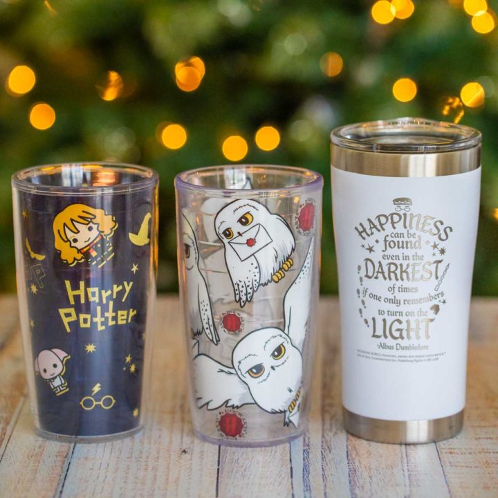 Three Harry Potter tumblers in front of a lit Christmas tree.