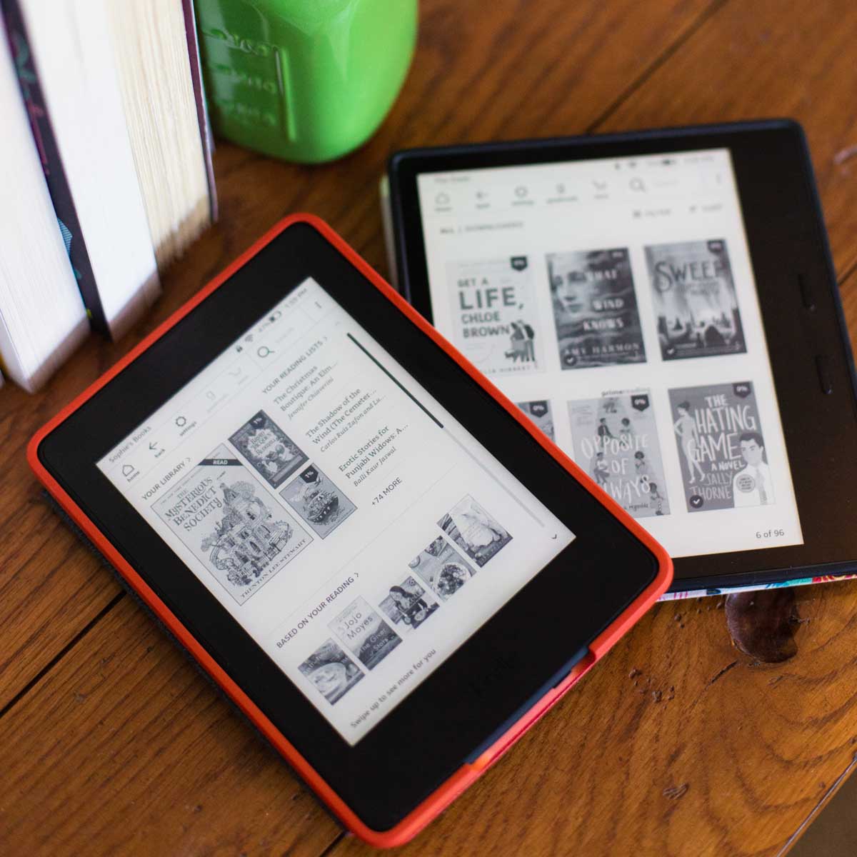 A Kindle Paperwhite and a Kindle Oasis sit on a table together.